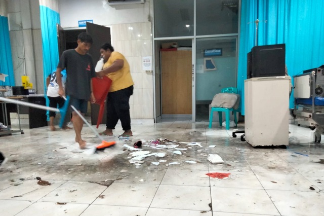 Petugas Kebersihan RSUD Chasan Boesoirie Ternate Membersihkan Ruangan dalam IGD yang Tergenang Air Hujan. (Rakyatmu)