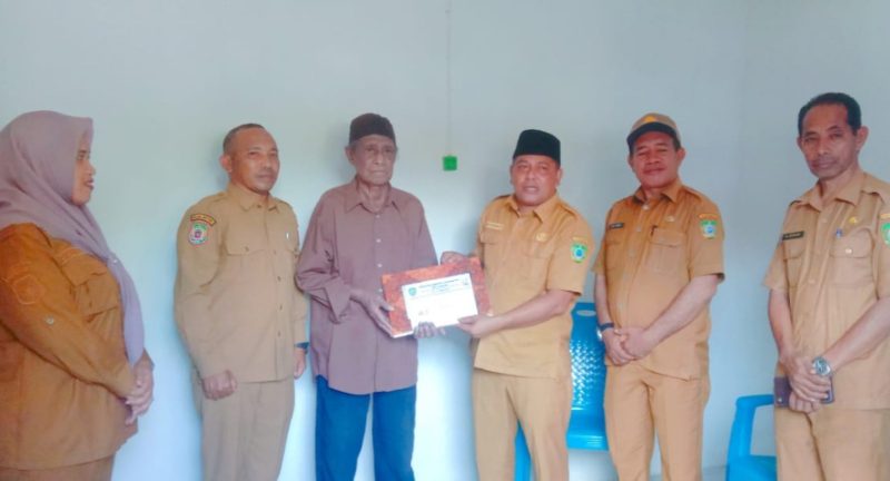 Sekretaris Daerah Kabupaten Kepulauan Sula Muhlis Soamole Menyerahkan Kado dari Bupati Fifian Adeningsih Mus Berupa Umroh dan Naik Haji kepada Salah Satu Tokoh Pemekaran Adam Mayau. (Rakyatmu)