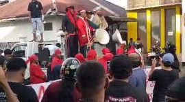 Foto: Zulkifli Marsaoly mengenakan pakaian sadaria warna crame disertai tuala talam saat menggelar aksi demonstrasi di depan Kantor KPU Maluku Utara. (Istimewa)