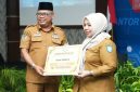 Sekprov Maluku Utara Samsudin A. Kadir Menyerahkan Penghargaan Terbaik I ke Kadinkes Kota Ternate Fathiyah Suma. (Rakyatmu)