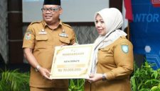 Sekprov Maluku Utara Samsudin A. Kadir Menyerahkan Penghargaan Terbaik I ke Kadinkes Kota Ternate Fathiyah Suma. (Rakyatmu)
