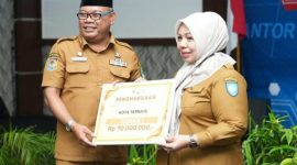 Sekprov Maluku Utara Samsudin A. Kadir Menyerahkan Penghargaan Terbaik I ke Kadinkes Kota Ternate Fathiyah Suma. (Rakyatmu)