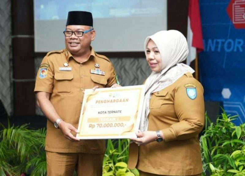 Sekprov Maluku Utara Samsudin A. Kadir Menyerahkan Penghargaan Terbaik I ke Kadinkes Kota Ternate Fathiyah Suma. (Rakyatmu)