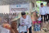 Wali Kota Ternate, M. Tauhid Soleman Menyerahkan Bantuan Sosial dan E-KTP kepada Ibu Labe Lahe di Acara Kampung Keluarga Berkulitas Pilot Project TP PKK Kota Ternate