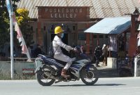 Seorang pekerja mengenakan masker melintas di depan Puskesmas Lelilef, Weda Tengah, Halmahera Tengah. Foto: Nurkholis Lamaau