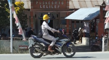 Seorang pekerja mengenakan masker melintas di depan Puskesmas Lelilef, Weda Tengah, Halmahera Tengah. Foto: Nurkholis Lamaau